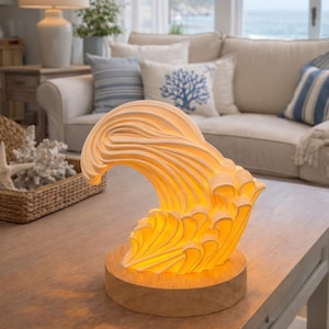 May include: A decorative wave-shaped lamp with a warm, yellow glow, set on a wooden base. The lamp's design mimics a breaking wave, creating a coastal or nautical theme. The lamp is placed on a wooden coffee table in a living room.