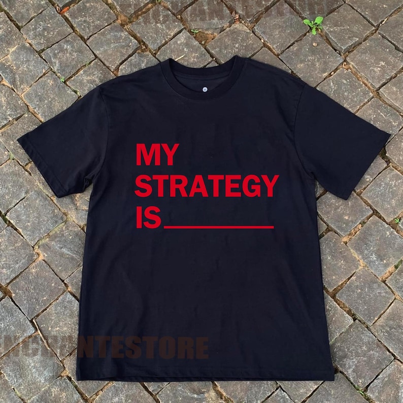 May include: Black t-shirt with the text "MY STRATEGY IS" in red.