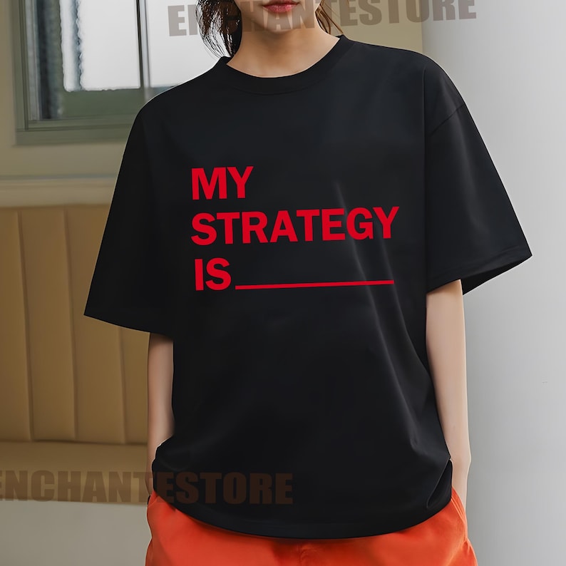 May include: Black t-shirt with red text that reads "My Strategy Is" with a blank line underneath.