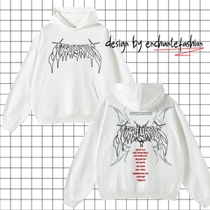 May include: White hooded sweatshirt with a black graphic print of the word "SURROUNDS" in a gothic font. The back of the sweatshirt has the same graphic print with the year "2025" above it and a list of cities in a smaller font below it.