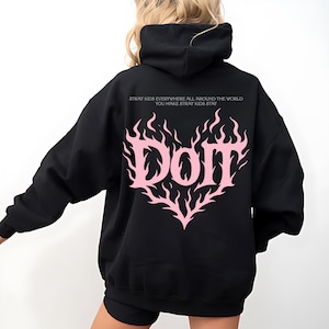 Puede incluir: Sudadera con capucha negra con un dise&ntilde;o de llama rosa en forma de coraz&oacute;n. La palabra "Dom" est&aacute; en el centro del coraz&oacute;n. Encima del coraz&oacute;n est&aacute; el texto "Stray Kids Everywhere All Around The World You Make Stray Kids Stay".