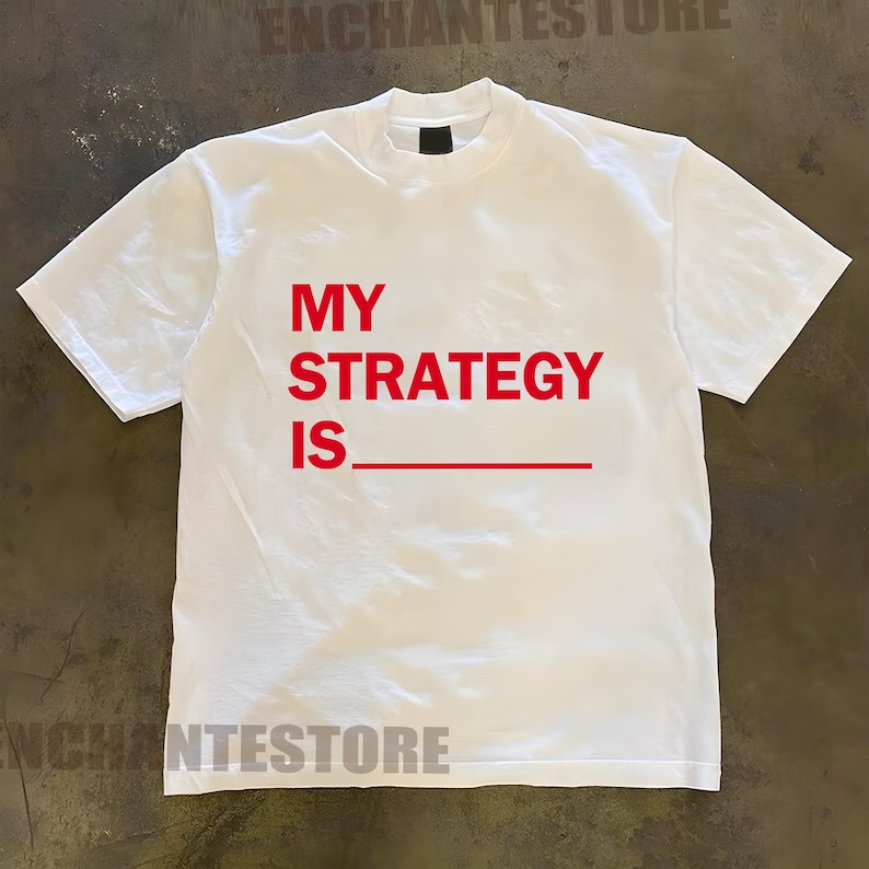 May include: White t-shirt with red text that reads "MY STRATEGY IS_"