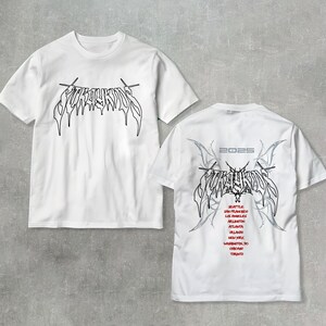 May include: Two white t-shirts with a black graphic print of the word "FURY" in a stylized font. The back of one shirt has the word "FURY" in the same font with a gray design and the text "2023" above it. The shirt also lists a tour schedule with cities including Seattle, San Francisco, Los Angeles, Atlanta, Orlando, New York, Washington DC, Chicago, and Toronto.