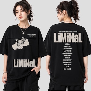 May include: A black short-sleeve t-shirt featuring a graphic print. The front displays a torn paper effect revealing a face, the text 2026-27 TAEMIN WORLD TOUR, and LIMINAL. The back lists tour cities including Seoul, San Jose, and Sao Paulo.