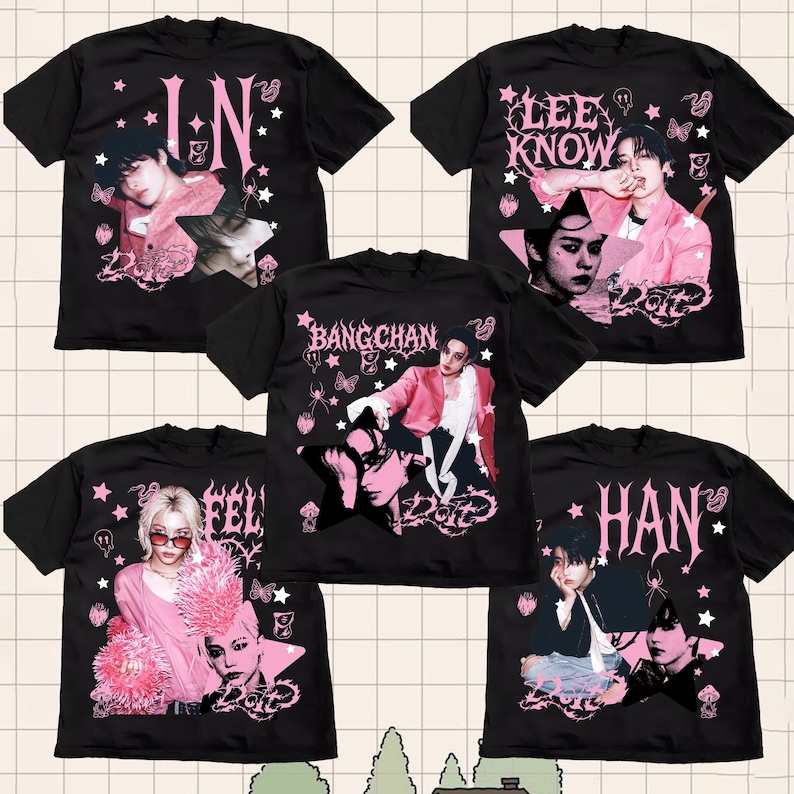 Pu&ograve; includere: T-shirt nere con grafiche rosa e bianche raffiguranti ritratti e nomi. I disegni includono testi come "IN", "LEE KNOW", "BANG CHAN", "FEL" e "HAN". Le magliette hanno un'estetica vintage e usurata con stelle, farfalle ed elementi a ragnatela.