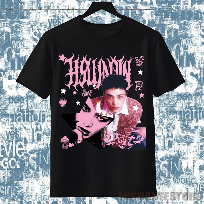 Pu&ograve; includere: T-shirt nera con un design grafico rosa. Il design presenta la parola "Hwaunnn" in un font stilizzato, un ritratto di una persona, stelle e altri elementi decorativi. La maglietta &egrave; appesa a una gruccia nera.