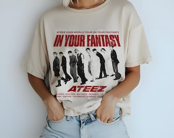 May include: A beige t-shirt with a black and white photo of a group of men on it. The text "ATEEZ 2025 WORLD TOUR [IN YOUR FANTASY] IN YOUR FANTASY ATEEZ" is printed on the shirt. The shirt is being worn by a person.