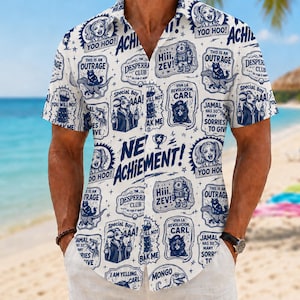 May include: A short-sleeved button-down shirt in white with an all-over dark blue graphic print. The pattern features various cartoon illustrations, including cats, astronauts, and goats, accompanied by text such as NEW ACHIEVEMENT, YOO HOO, and VIVA LA REVOLUCION, CARL.