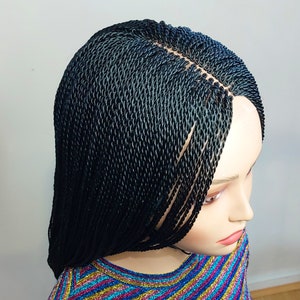 May include: Black braided wig with a lace front. The wig is styled in a long, straight style.