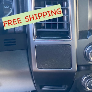 May include: A black plastic car dashboard trim piece with a textured surface. The trim piece is rectangular and has a silver border. The text "FREE SHIPPING" is visible in red letters on a green background.