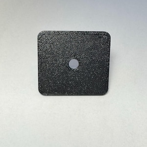 May include: A black square-shaped plastic object with a small round hole in the center.