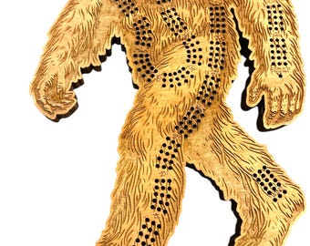 May include: A wooden cribbage board shaped like a Sasquatch, with a brown stain. The board has a path of numbered holes for playing cribbage.