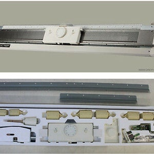 May include: A white knitting machine with a metal needle bed and a control panel. The machine is shown with its accessories, including gray metal bars and various small components in a white tray. The image is taken from above.