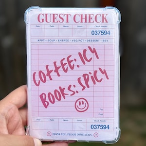 May include: A pink and white phone case featuring a "Guest Check" design with handwritten text "COFFEE: ICY BOOKS: SPICY". The case has a clear, protective border and includes a check number and a smiley face.