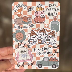 May include: A rectangular sticker with a fall theme. It features illustrations of pumpkins, ghosts, coffee, books, and the phrases "All I need is," "Coffee & a good book," "Cuddle up and read," and "Hey there, Pumpkin."