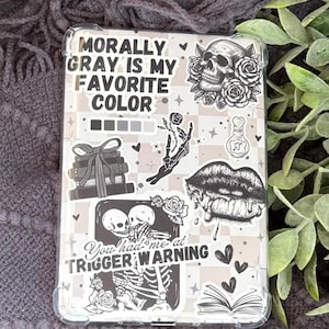 May include: A clear phone case with a gray and white checkered pattern. The case features various black and white stickers, including a skull with roses, a skeleton couple, and the text "Morally Gray is My Favorite Color."