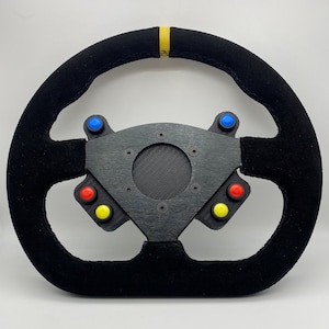Pode incluir: Volante de corrida preto com uma faixa amarela, uma placa central de fibra de carbono e seis botões em vermelho, azul e amarelo.