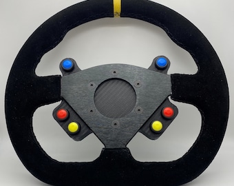 May include: Black racing steering wheel with a yellow stripe, a carbon fiber center plate, and six buttons in red, blue, and yellow.