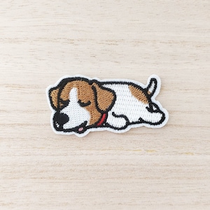 May include: Embroidered iron-on patch of a brown and white dog sleeping. The dog has a red collar and is lying on its side with its head resting on its paws.