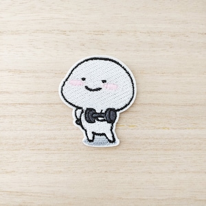 May include: White embroidered patch of a cartoon character lifting a dumbbell. The character has a round head with a smiling face and rosy cheeks.