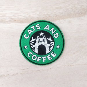 Peut inclure: Patch brodé vert et blanc avec le texte "Cats and Coffee" et un chat de dessin animé à l'intérieur d'une étoile.