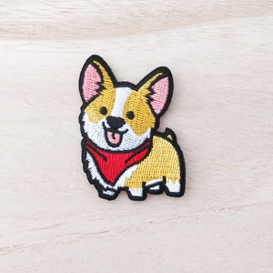 May include: Embroidered patch of a cartoon corgi wearing a red bandana. The corgi is yellow with white markings and has a pink nose and ears.
