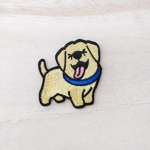 May include: Embroidered iron-on patch of a yellow labrador retriever puppy with a blue collar and a pink tongue sticking out.