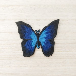 May include: An embroidered butterfly patch in blue and black.
