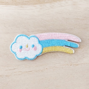 May include: A white cloud with a smiling face and pink cheeks is attached to a rainbow-coloured shooting star. The star is pink, blue, and yellow.