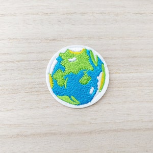May include: A white embroidered patch with a blue and green globe design.