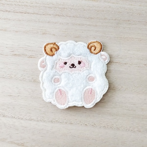May include: White fluffy sheep applique with pink feet and brown curled horns. The sheep has a cute embroidered face with pink cheeks.