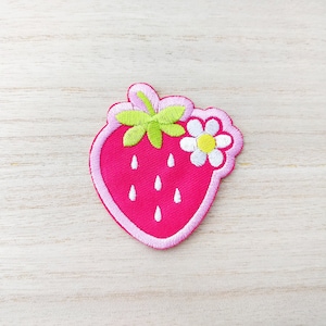 Peut inclure: Un patch brodé de fraise rose avec une fleur blanche et des feuilles vertes.