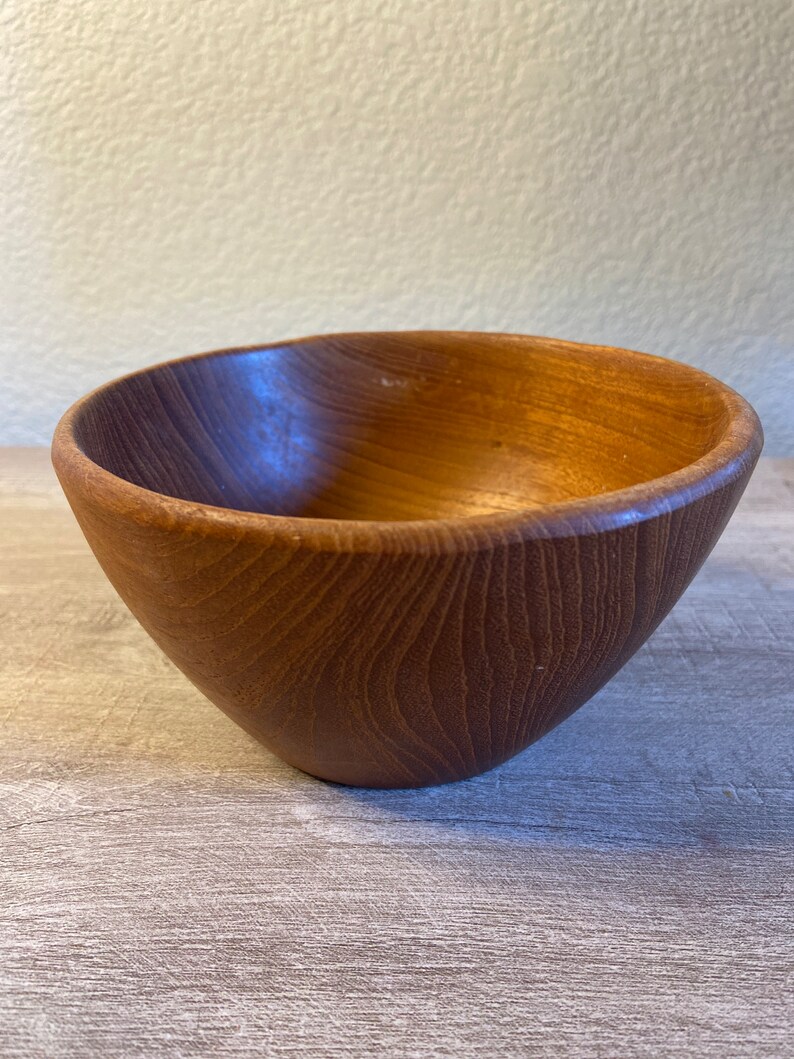 May include: A wooden bowl with a natural brown finish. The bowl is round and has a smooth, slightly curved surface.