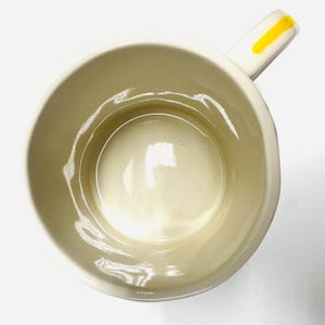 May include: A white ceramic mug with a black handle and the text "But First, Coffee" in a black, handwritten-style font. The mug is on a white surface.