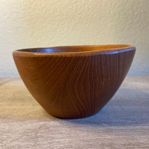 May include: A brown wooden bowl with a smooth, rounded shape and a natural wood grain pattern.