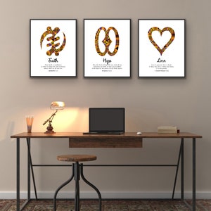 May include: Three framed prints with African Adinkra symbols and inspirational quotes. The prints are hung on a beige wall above a wooden desk with a lamp and a laptop. The quotes are "Faith", "Hope", and "Love".