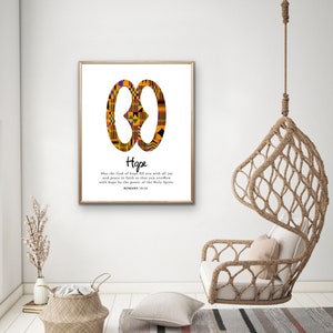 May include: A printable wall art design featuring a symbol of hope in the Adinkra style, with a quote from Romans 15:13. The symbol is in yellow, orange, red, and black colors. The background is white.