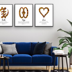 May include: Three framed prints with African Adinkra symbols and inspirational quotes. The prints feature the symbols for faith, hope, and love, each with a corresponding Bible verse. The prints are displayed on a white wall above a blue sofa.