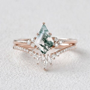 Op de afbeelding: Een verlovingsring van roségoud met een groene mosagaat-middelsteen en een delicate halo van diamanten. De band is bezet met kleine diamanten in pavé-setting.