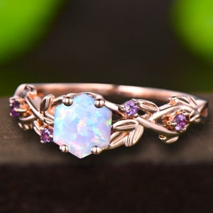May include: A rose gold ring with a white opal gemstone and small purple gemstones set in a delicate vine design.