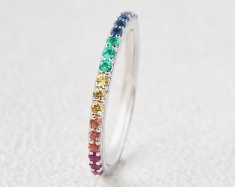 Puede incluir: Un fino anillo de banda de plata con un arcoíris de pequeñas piedras preciosas engastadas en una fila alrededor de la banda.
