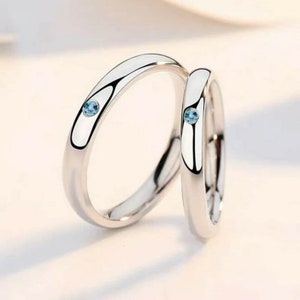 May include: Two silver rings with a small blue gemstone on each. The rings are simple and elegant.