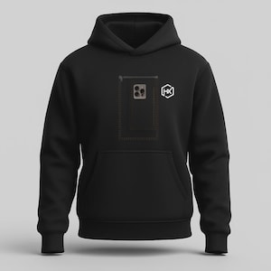 Op de afbeelding: Een zwarte hoodie met een grafische print op de borst. Het ontwerp bevat de omtrek van een rechthoekige zak met een rits, een illustratie van een cameramodule van een smartphone en een wit zeshoekig logo met de letters HX.