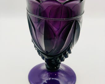 Jarrón antiguo de cristal color amatista sobre pedestal con bordes festoneados.