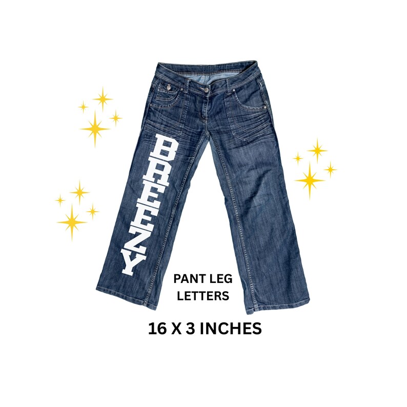 May include: Blue denim jeans with white block letters spelling "BREENZY" down the left pant leg. The jeans are 16 x 3 inches. The jeans have pockets and a button closure.