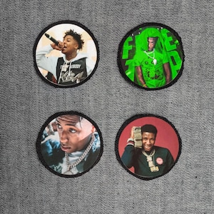 May include: Four round patches featuring images of a person. The patches have black borders and are set against a gray background. The images include a person holding a microphone, wearing a green shirt, and holding money.