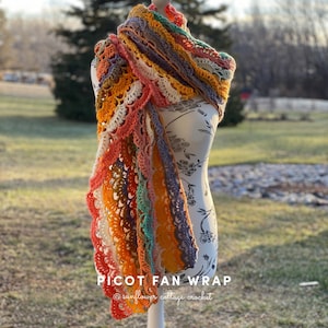 May include: A colorful crochet shawl with a picot edge, draped over a white dress form. The shawl is made with a variety of colors, including orange, yellow, green, and purple. The text "PICOT FAN WRAP" and "@sunflower_cottage_crochet" is visible at the bottom of the image.