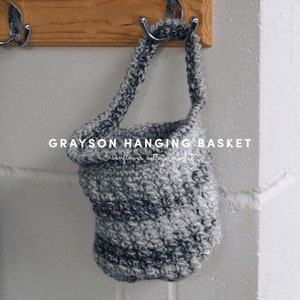 May include: A gray and white crocheted hanging basket with the text "GRAYSON HANGING BASKET © sunflower cottage crochet" on the front.
