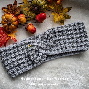 Może przedstawiać: Szary i biały opaska na uszy w kratę. Opaska jest szydełkowana i ma węzeł w środku. Tekst "Houndstooth Ear Warmer PDF pattern only" znajduje się na dole obrazu.
