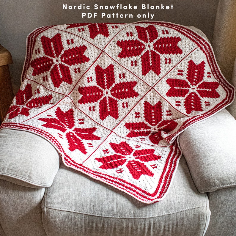Puede incluir: Una manta de crochet de copo de nieve roja y blanca con un borde. La manta est&aacute; doblada y drapeada sobre una silla. El texto "Nordic Snowflake Blanket PDF Pattern only" es visible en la parte superior de la imagen.